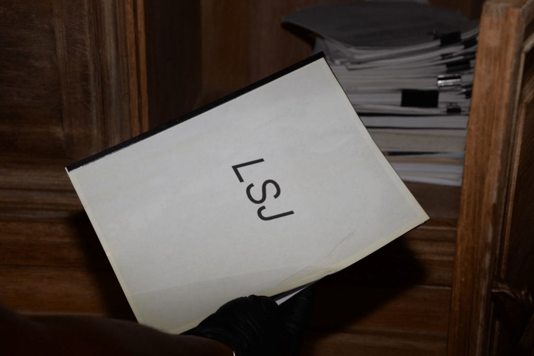 A hand holding a document in front of a stack of papers. Both programs demand paperwork, but different paperwork. Photo: Wikimedia Commons, public domain.