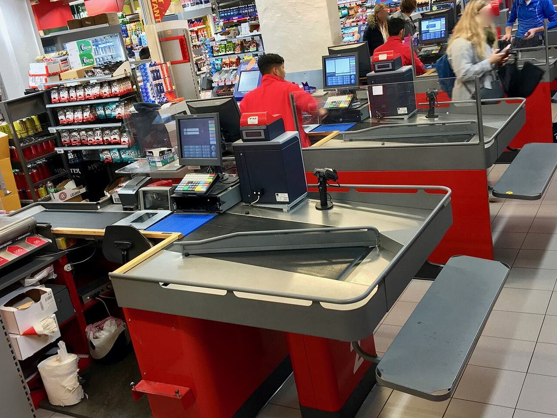 A cashier at a supermarket checkout. Part-time and lower-paid work can fit under the SGA limit. Photo: Wikimedia Commons, CC BY-SA 4.0.