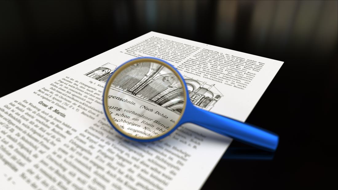 A magnifying glass over paper. At every appeal level, the file is re-examined. Photo: Wikimedia Commons, CC BY-SA 3.0.